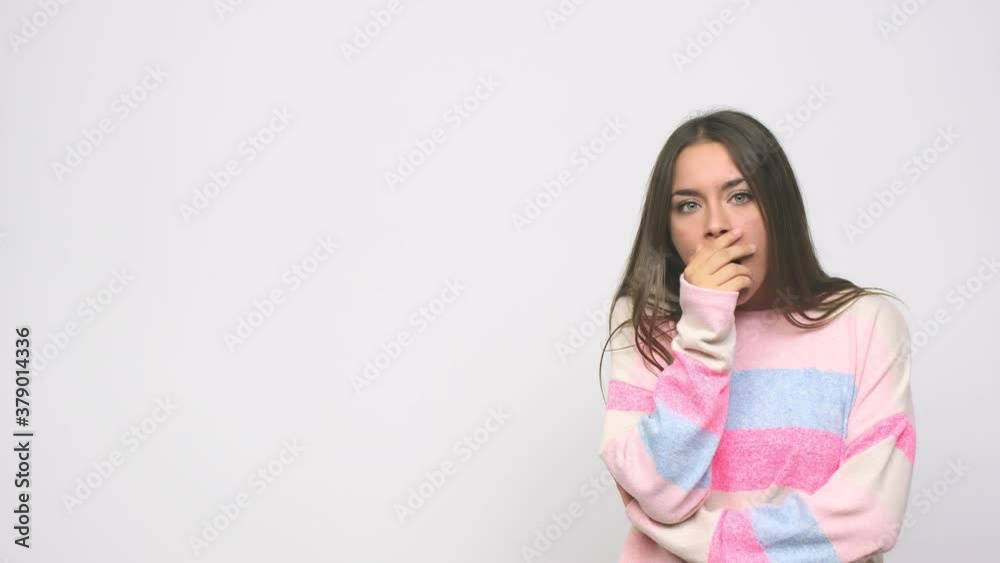 Young cute woman thoughtful looking to a copy space covering mouth with hand Young cute woman thoughtful looking to a copy space covering mouth with hand