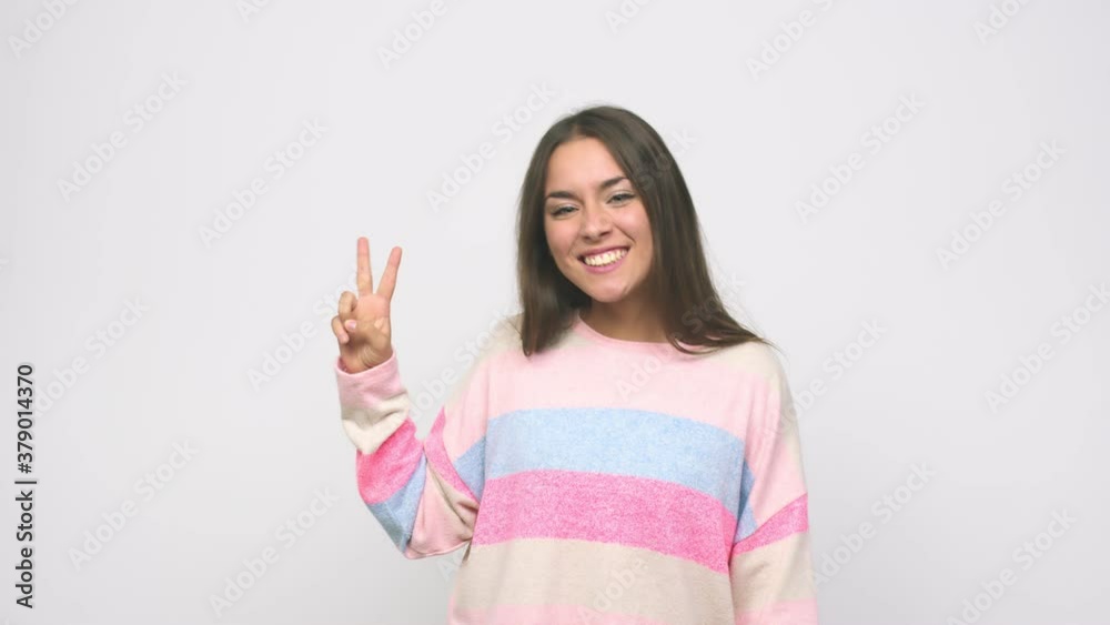 Young cute woman showing victory sign and smiling broadly Young cute woman showing victory sign and smiling broadly