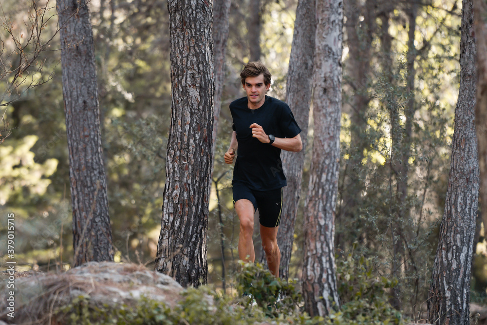 Young athlete running in the forest with a black outfit Young athlete running in the forest with a black outfit