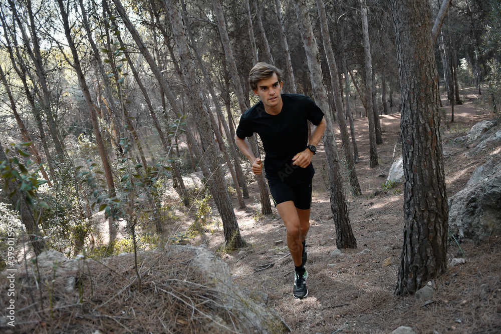 Fototapeta premium Young athlete running in the forest with a black outfit