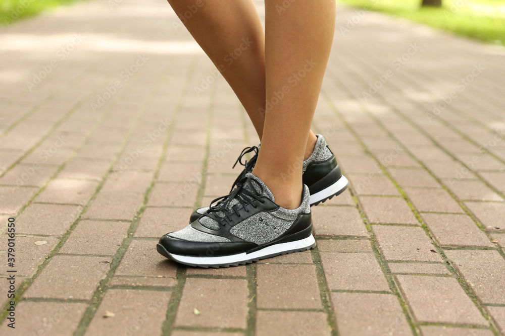 woman's legs in sport sneakers outdoor close up