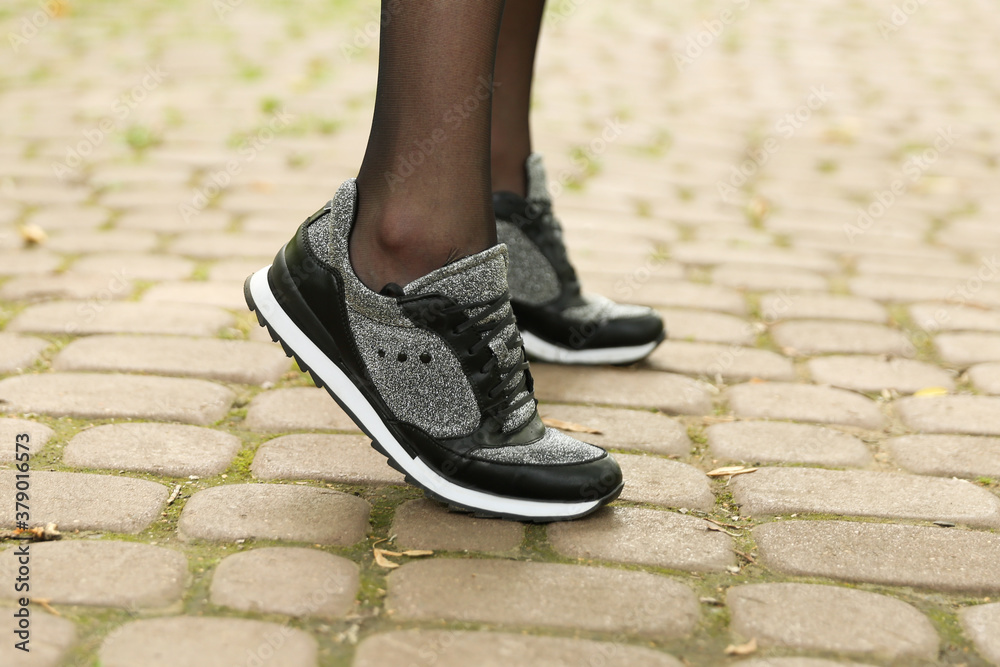woman's legs in black pantyhose and black sneakers outdoor close up woman's legs in black pantyhose and black sneakers outdoor close up