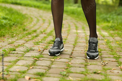 woman's legs in black pantyhose and black sneakers outdoor close up © Петр Смагин