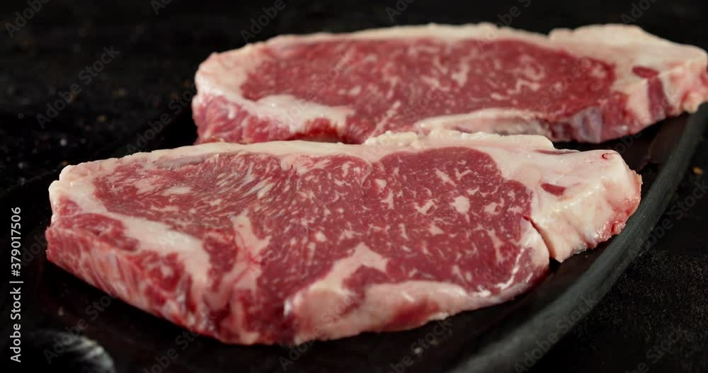 Raw beef striploin steak on a cutting board rotates. Raw beef striploin steak on a cutting board rotates.