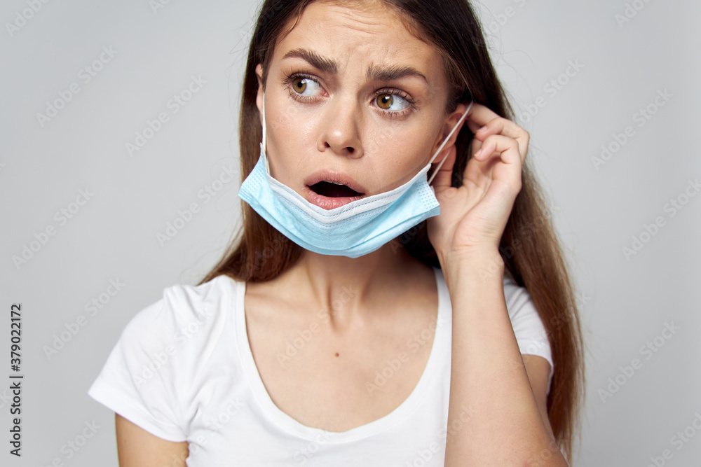 Brunette putting on a medical mask on her face look towards emotions Brunette putting on a medical mask on her face look towards emotions