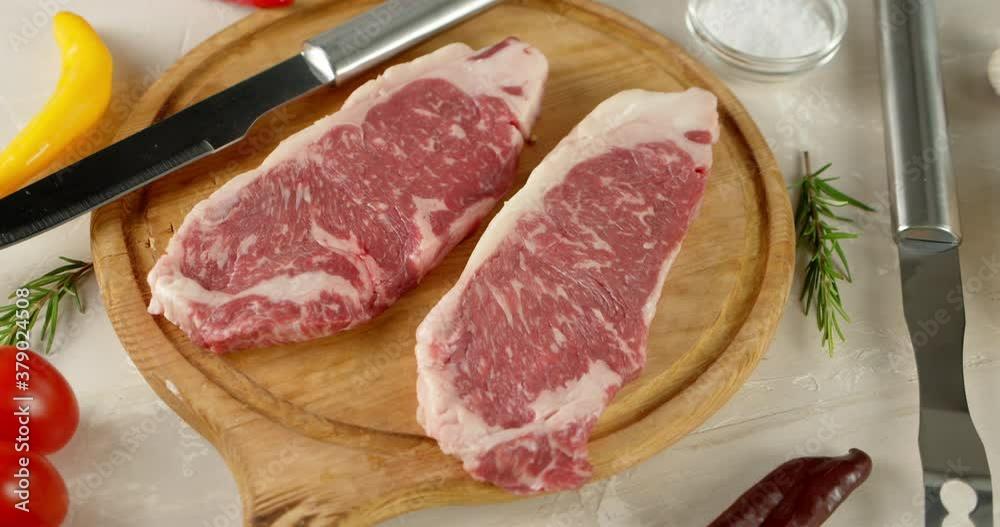 Raw steak beef striploin on a cutting board rotates. Raw steak beef striploin on a cutting board rotates.