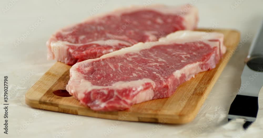 Steak striploin raw on a wooden cutting board rotate. Steak striploin raw on a wooden cutting board rotate.