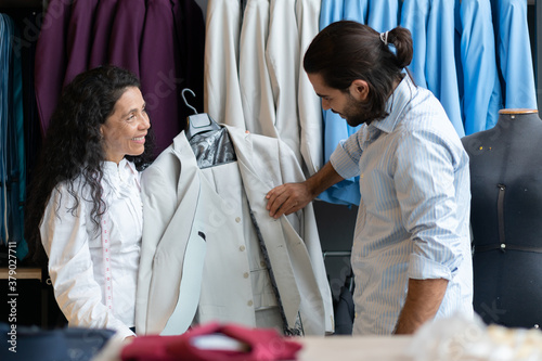 Photography Happy brazilian female entrepreneur with customer showing jacket inside business store