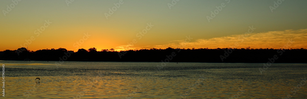 Colourful winter sunset in July, with silhouette and reflection over the Noosa River, Noosaville, Queensland, Australia