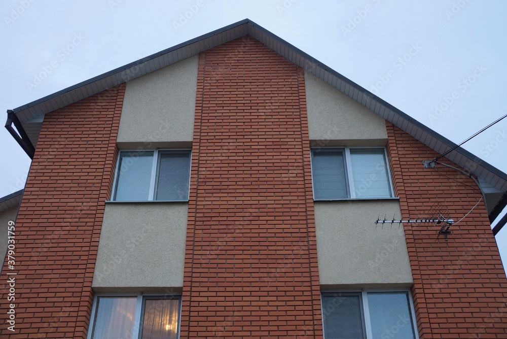 facade of a brown private brick house with windows against the sky in the evening street