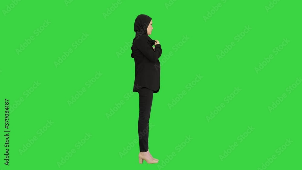 Business woman in hijab standing fixing her hijab on a Green Screen, Chroma Key. Business woman in hijab standing fixing her hijab on a Green Screen, Chroma Key.