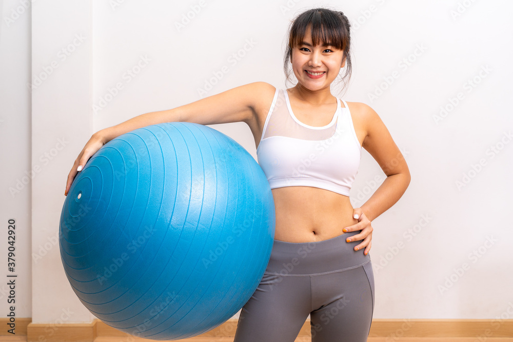 Young happy Asian woman posing and smiling for camera during her exercise Young happy Asian woman posing and smiling for camera during her exercise