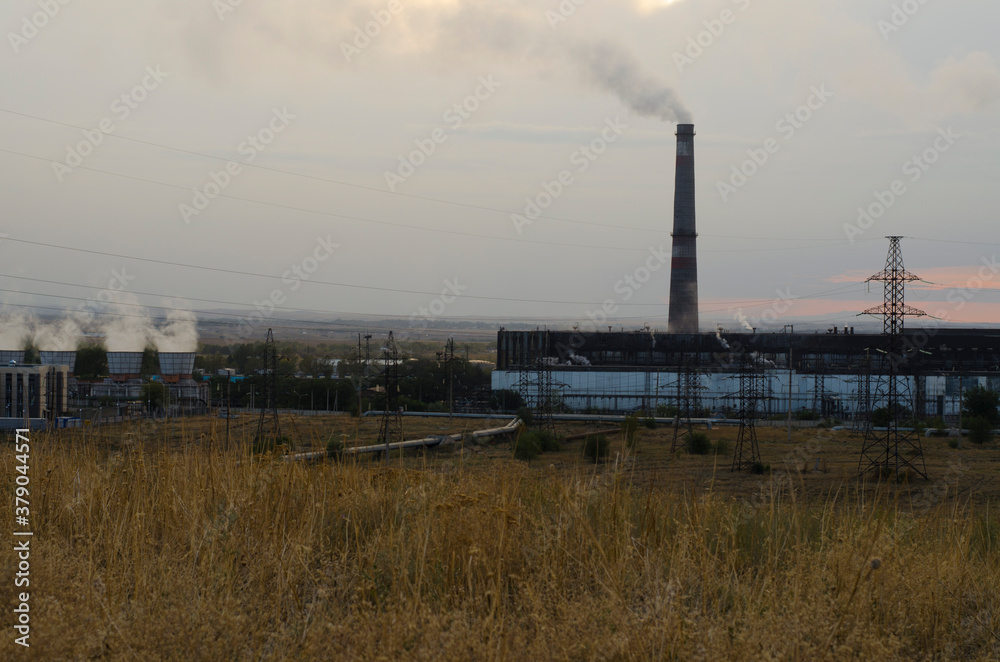 Large chimneys of an industrial plant emit smoke into the atmosphere. Ecology problem, environmental pollution. Heat station.