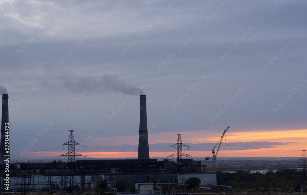 Industrial landscape at sunset, pipes and smoke. Smog and environmental problems.