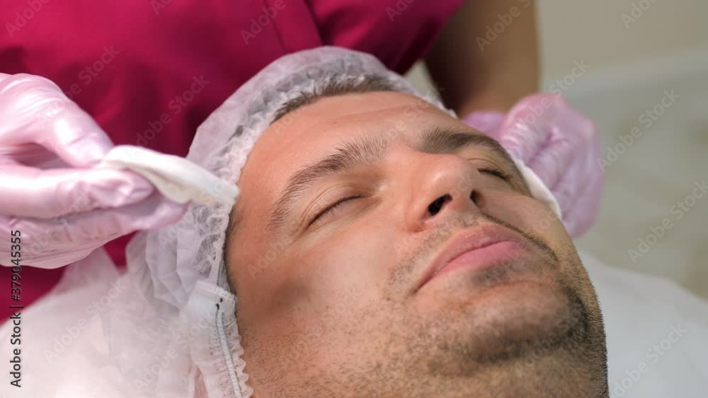 Cosmetician applying peeling to the face of young handsome man Cosmetician applying peeling to the face of young handsome man