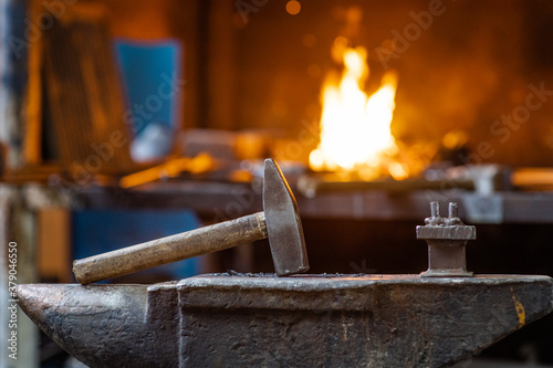Blacksmith hammer on the anvil against the background of fire