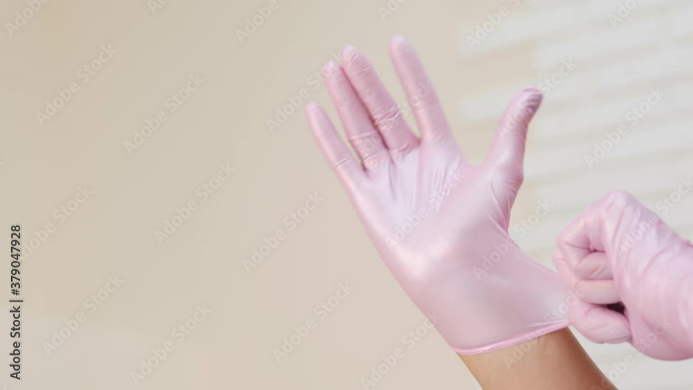 Cosmetologist wearing latex pink gloves on her hands close up Cosmetologist wearing latex pink gloves on her hands close up