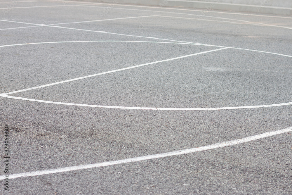 White line markings for sports on the black asphalt floor.
