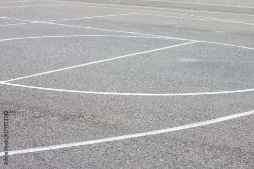 White line markings for sports on the black asphalt floor.