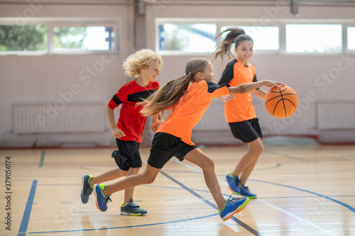 Kids in bright sportswear playing basketball together and feeling competitive © zinkevych