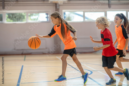 Kids in bright sportswear playing basketball together and feeling energized © zinkevych