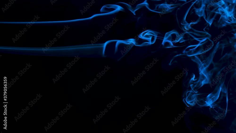 A horizontal plume of smoke against a blue backlit black background creating abstract lines. Close up. Slow motion. A horizontal plume of smoke against a blue backlit black background creating abstract lines. Close up. Slow motion.