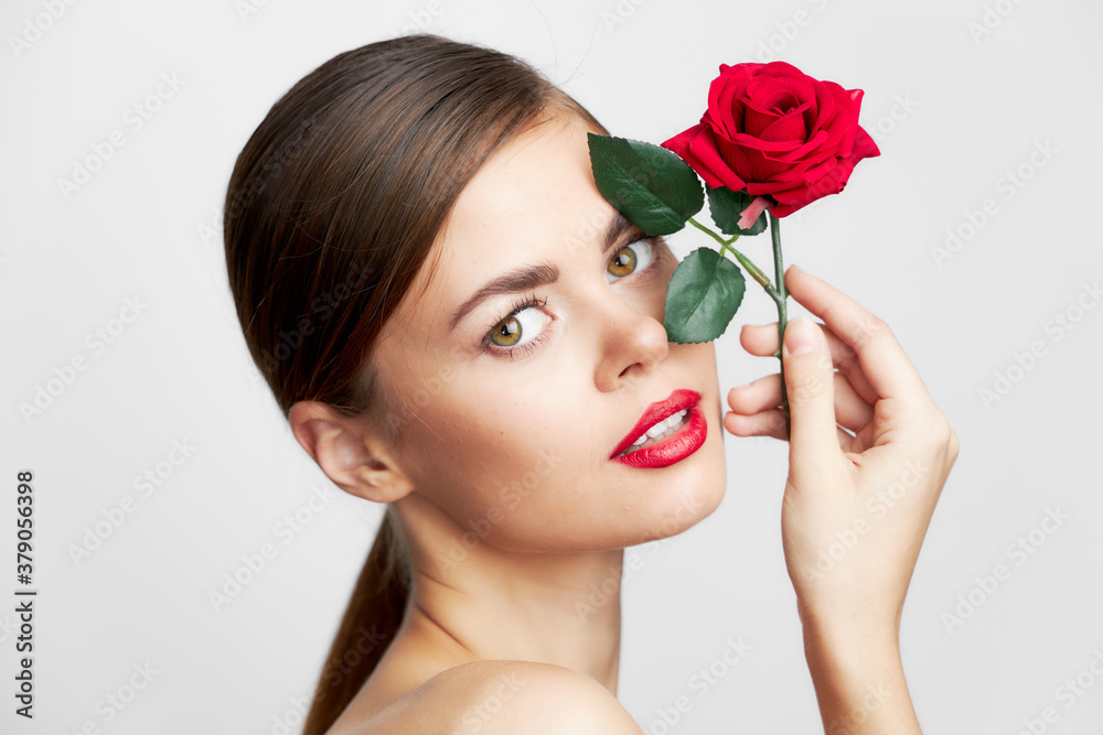 Fototapeta premium Brunette with bare shoulders holding a rose near his face body care 