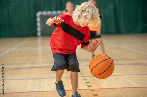 A blonde boy playing with a ball and looking involved