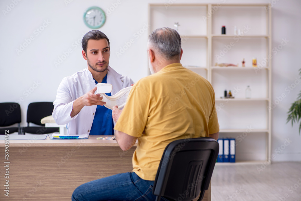 Old neck injured man visiting young male doctor Old neck injured man visiting young male doctor