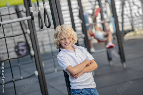 Blonde boy in white tshirt standing with arms crossed