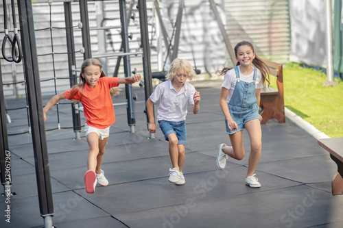 Three friends running at the playground and feeling excited