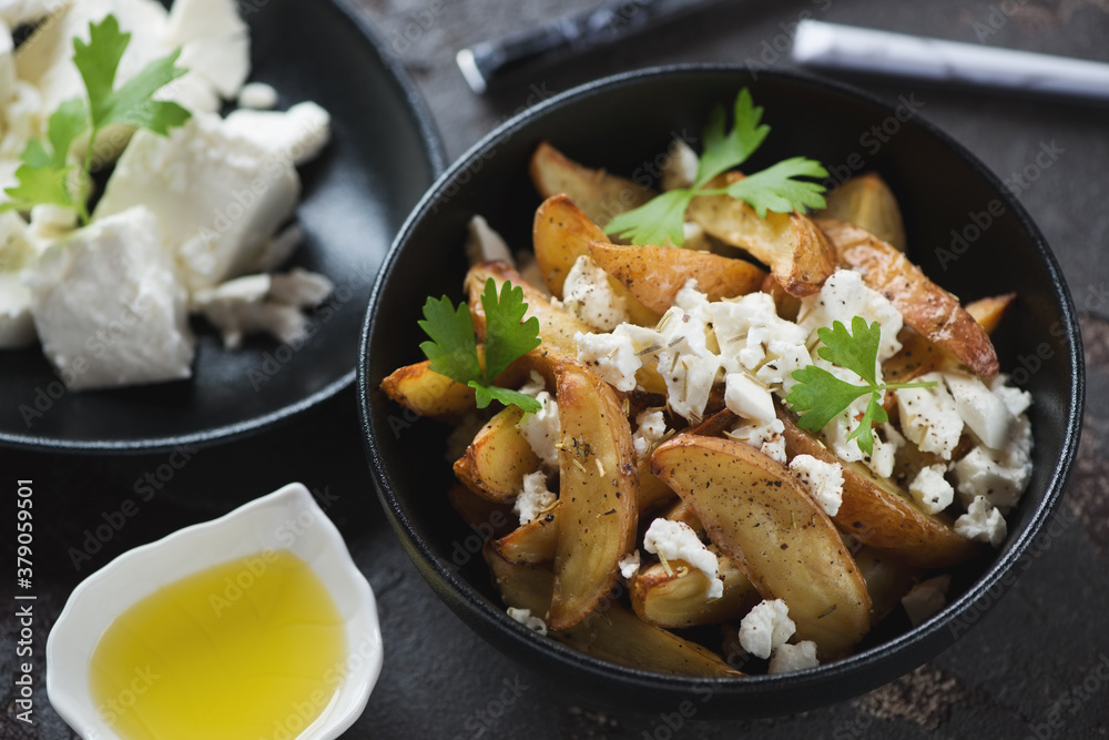 Greek style baked potato wedges with feta cheese and olive oil, closeup, selective focus, studio shot Greek style baked potato wedges with feta cheese and olive oil, closeup, selective focus, studio shot