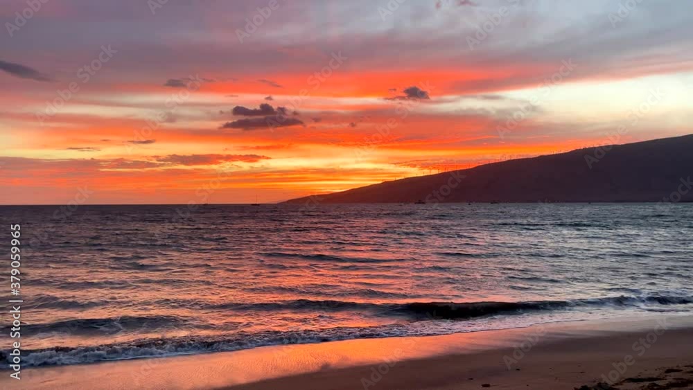 Dramatic orange Hawaii sunset with rolling ocean and small waves in foreground and part of island silhouette in the distance give filling of isolation Dramatic orange Hawaii sunset with rolling ocean and small waves in foreground and part of island silhouette in the distance give filling of isolation