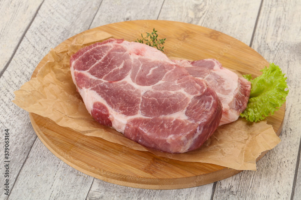 Raw pork steak over wooden board