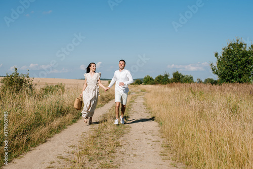 Young couple in the wheat field on sunny summer day. Couple in love have fun in golden field. Romantic couple in casual clothe outdoodrs on boundless field © rostyslav84