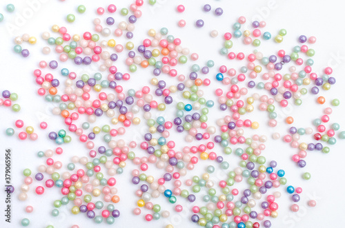 Perlas, chispitas y grageas para decoración de tartas esparcidas sobre fondo blanco.
 photo