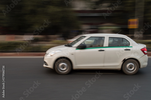 panning technique of white car which is going somewhere at evening on the road