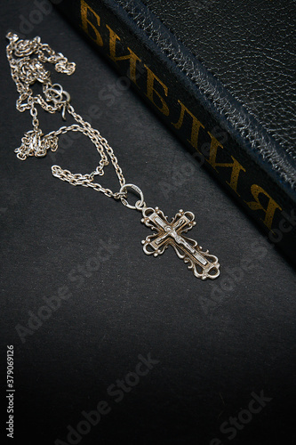 The cross lies next to the bible, black and white.