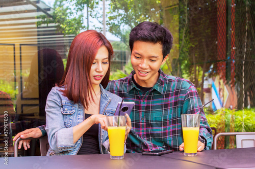 Smiling young couple using a smartphone in cafe