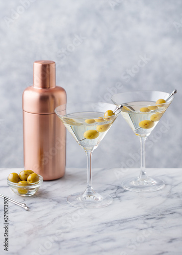 Martini cocktail with olives and bar shaker. Marble background. Copy space.