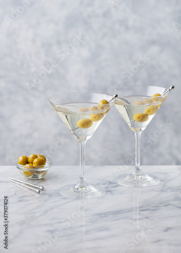 Martini cocktail with green olives on marble table background. Copy space.