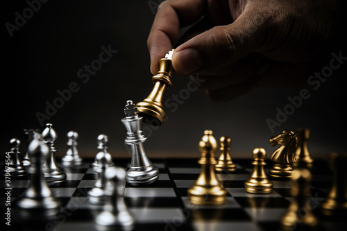 Close up hand choose gold chess to fight with silver chess team on chess board Concept of business strategic plan and professional teamwork and challenge management.