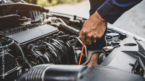 Auto mechanic are checking vehicle engine oil level to changing car engine oil concepts of maintenance repair service and car insurance. © Eakrin