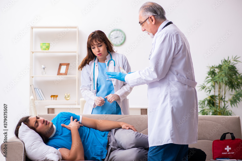 Obraz premium Two doctors visiting sick young man at home