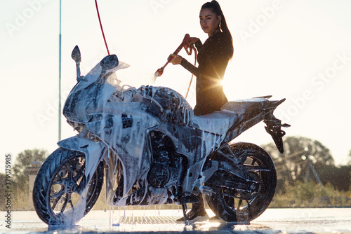 Εκτύπωση καμβά Beautiful girl washes a motorcycle at self service car wash with high pressure water