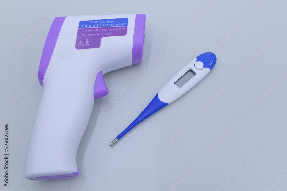 Non-contact infrared thermometer and electronic thermometer on a grey background.Vaccination against the virus. Non-contact infrared thermometer and electronic thermometer on a grey background.Vaccination against the virus.
