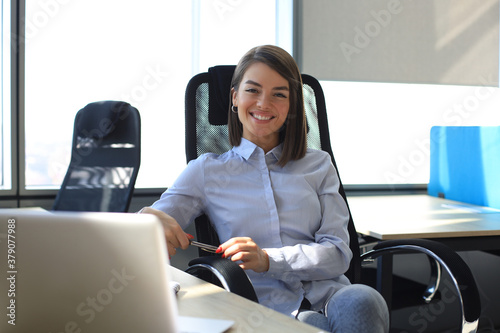 Beautiful smiling business woman is sitting in the office and looking at camera