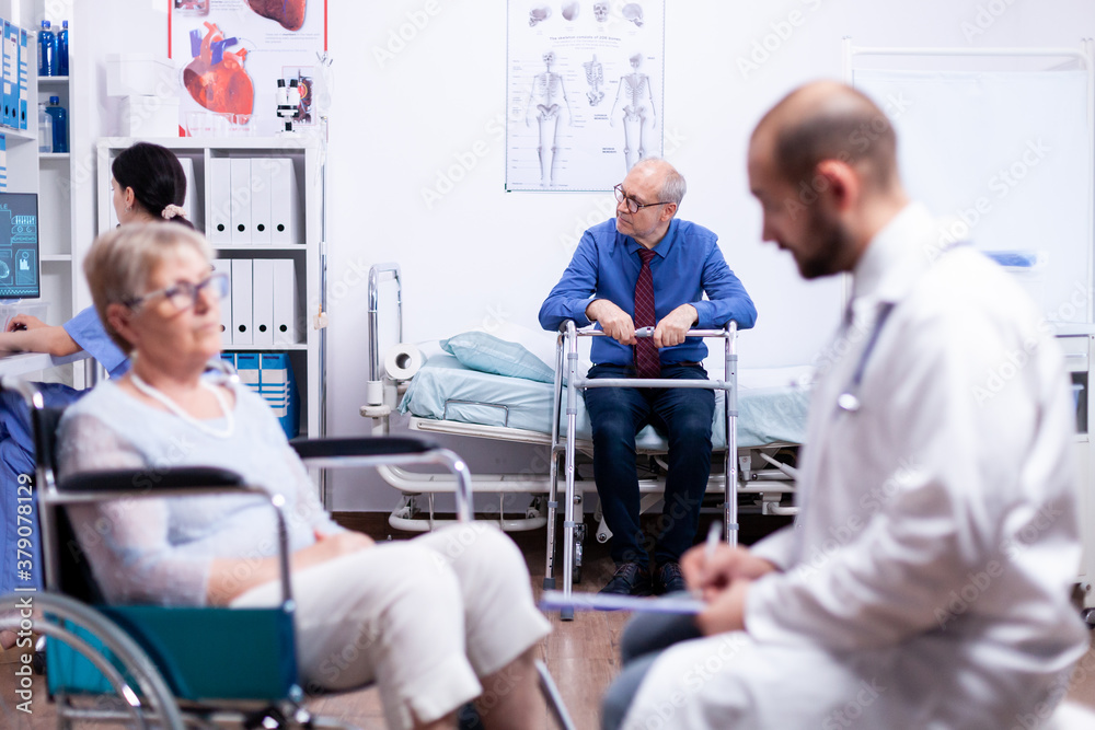 Obraz premium Senior man sitting on hospital bed with walking frame wainting for consultation. Man with disabilities ,walking frame sitting in hospital bed. Health care system, clinic patients.