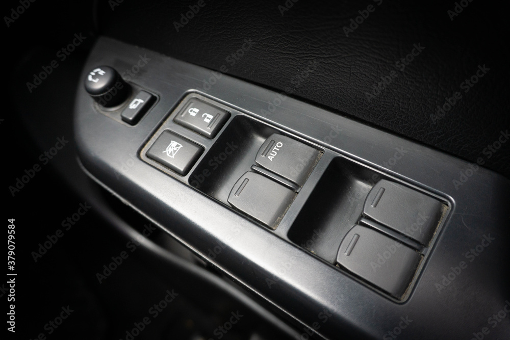 Сlose-up of the car black interior: the side door buttons: window adjustment buttons, door lock and other buttons.