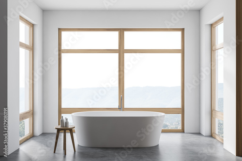 Modern white bathroom interior with tub and windows